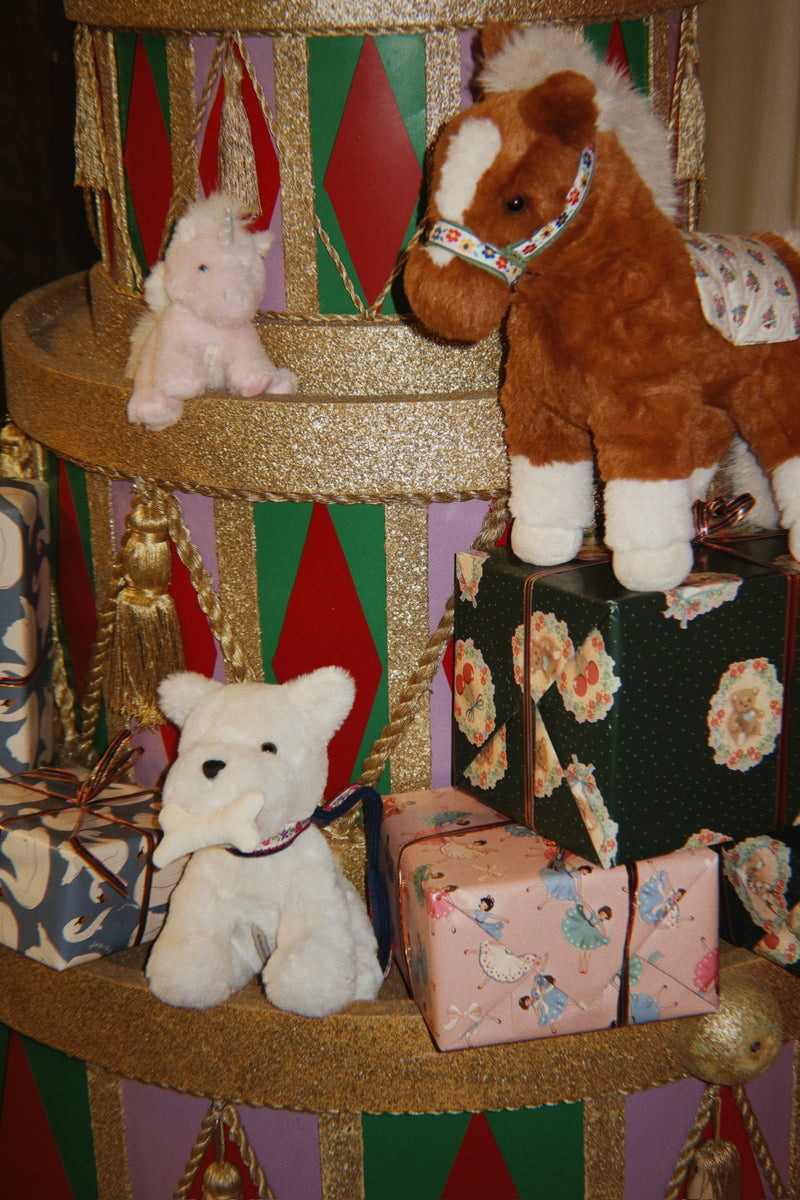 Plush horse, teddy bear and unicorn beside wrapped Christmas gifts