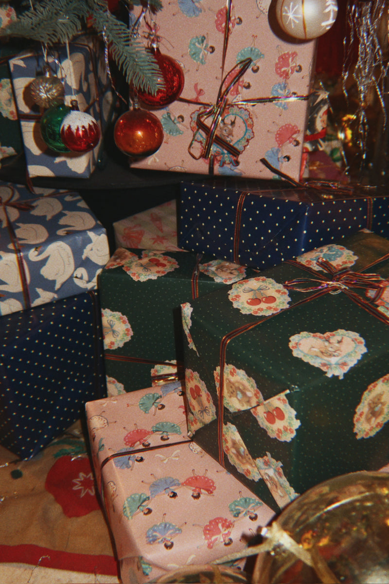 Christmas presents in green, pink and blue printed wrapping paper beneath festive ornaments